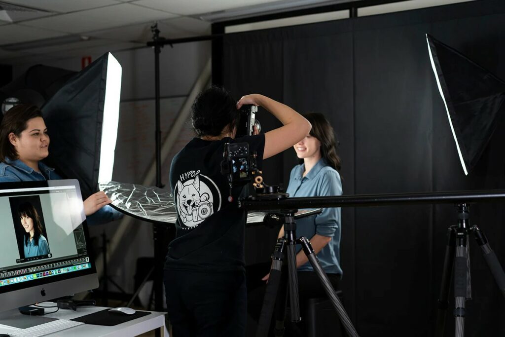 A professional photographer capturing a headshot in a studio with lighting equipment.