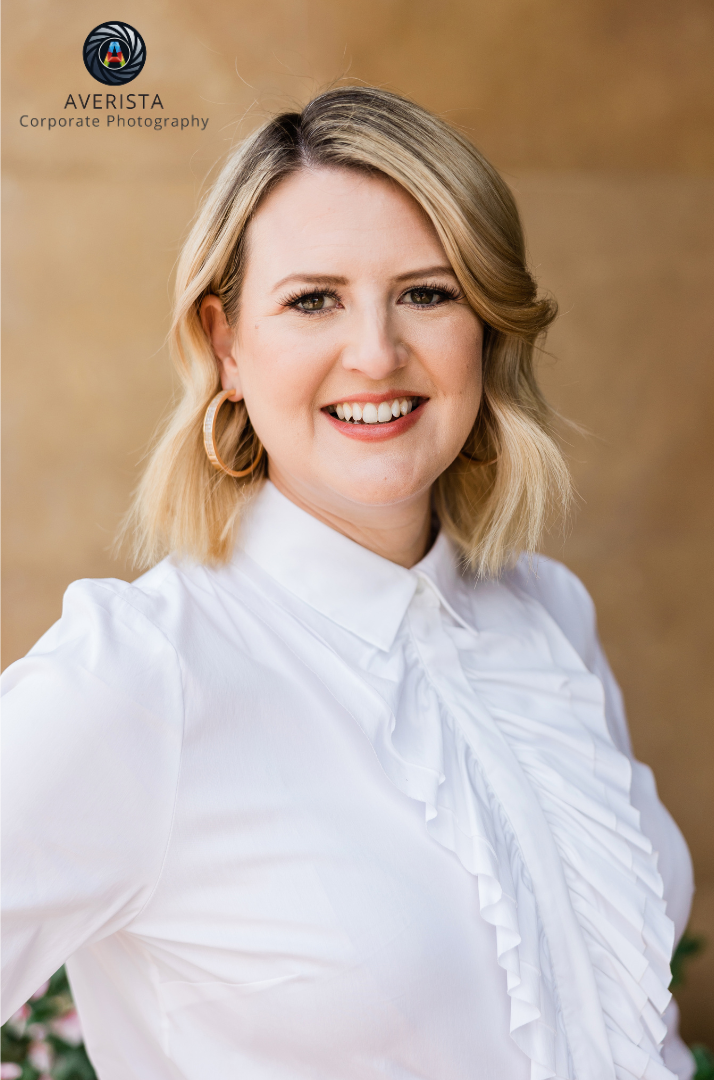 A professional headshot of a confident individual with a neutral background.