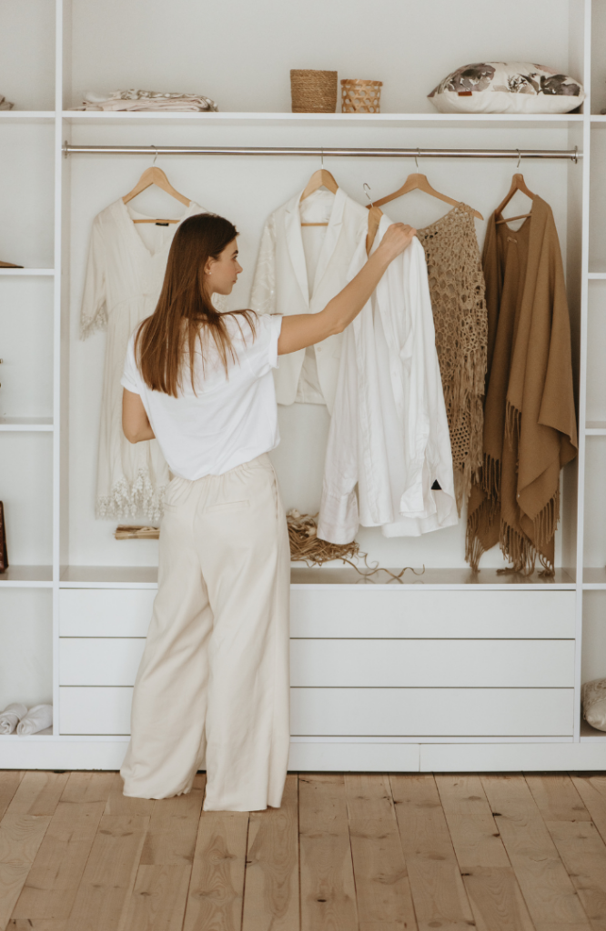 Professional woman choosing between outfits in front of a wardrobe for a headshot photo session.